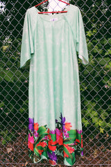 Women's vintage 1970's Butterfield 8, Made in USA label bell sleeved maxi length dress in light pastel green with Hawaiian floral print on the hem.