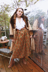 Women's vintage 1970's maxi length velvet skirt with an elastic waistband and matching tie belt. Orange with all over multicolored paisley print.