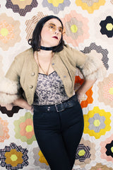 Women's vintage 1970's cropped fit tan suede jacket with short sleeves and two snap button closure in the front. Sleeves have a cream fur trim.