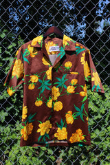 Men's vintage 1980's Hilo Hatties Hawaii label short sleeve button up floral print Hawaiian shirt in silky polyester material. Brown with all over yellow flowers.