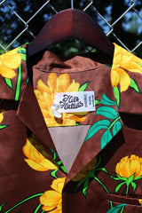 Men's vintage 1980's Hilo Hatties Hawaii label short sleeve button up floral print Hawaiian shirt in silky polyester material. Brown with all over yellow flowers.