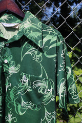 Men's vintage 1970's Grand Slam Munsignwear label short sleeve half button closure shirt with dagger collar in green with all over print. Polyester material.
