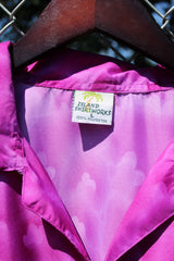 Men's vintage 1990's Island Shirtworks short sleeve button up Hawaiian print shirt in lightweight polyester material in purple, blue, and red with palm trees.