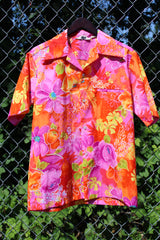 Men's or women's vintage 1970's Reef, Made in Hawaii label short sleeve button up Hawaiian print shirt in polyester material. Bright pink, orange, and yellow colors.