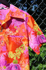 Men's or women's vintage 1970's Reef, Made in Hawaii label short sleeve button up Hawaiian print shirt in polyester material. Bright pink, orange, and yellow colors.