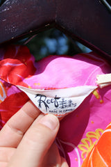 Men's or women's vintage 1970's Reef, Made in Hawaii label short sleeve button up Hawaiian print shirt in polyester material. Bright pink, orange, and yellow colors.