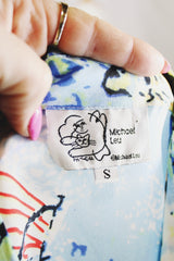 Women's vintage 1980's Michael Leu label long sleeve button up blouse with small collar, white buttons, and all over novelty print in a silk material.