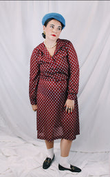 Women's vintage 1970's long sleeve midi length lightweight polyester dress with v shaped neckline and collar. Cinched at waist with tie. Maroon with all over blue and tan print.