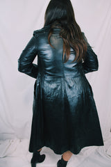 Women's vintage 1970's knee length long sleeve black leather trench coat with double lapel and button front closure.
