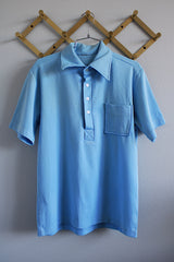 Men's or women's vintage 1970's short sleeve baby blue polyester material polo shirt with half button closure and red glittery wording on the back