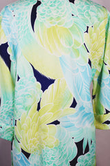 Women's vintage 1970's long sleeve button up tunic blouse with all over green and navy floral print. Flared sleeved and fabric covered buttons.