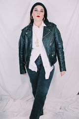 Men's or women's vintage 1980's long sleeve black leather motorcycle jacket with silver hardware. Zipper front closure and pockets.