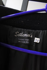 Men's or women's vintage 2000's Settlemein's, Portland, Oregon label long sleeve black varsity letterman jacket with yellow trim.