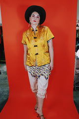 Women's vintage 1960's short sleeve gold yellow stain button up blouse with black trim and black fabric buttons.