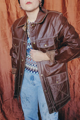 Women's or men 's vintage 1970's Montgomery Ward label long sleeve chocolate brown colored leather jacket with contrast stitching and popper buttons.