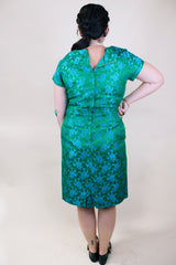 Women's vintage 1960's short sleeve midi length green and blue stain dress. Subtle floral print and scalloped waist. Zipper in the back.
