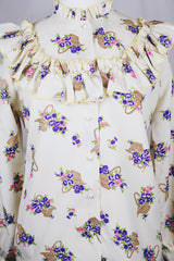 Women's vintage 1980's Val Lanne's label long sleeve button up blouse with ruffle details and pearl buttons. Cream color with all over purple floral print.