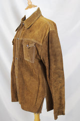 Men's or women's vintage 1970's long sleeve light brown tan colored suede jacket. Has silver snap buttons, contrast stitching, and a dagger collar.