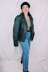 Men's or women's vintage 1980's long sleeve black leather moto jacket with all over silver hardware. Snap buttons, pockets with zippers, and zipper closure.