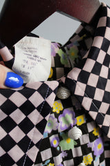 Women's vintage 1970's short sleeve puff sleeve bodysuit with collar in a black and purple checkered print and florals.