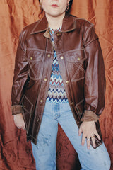 Women's or men 's vintage 1970's Montgomery Ward label long sleeve chocolate brown colored leather jacket with contrast stitching and popper buttons.