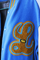 Men's or women's vintage 1994 Settlemien's, Portland, Oregon label long sleeve baby blue and cream varsity letterman jacket with yellow trim in leather and wool material.