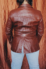 Women's or men's vintage 1970's chocolate brown colored leather jacket with leather buttons and double lapel.