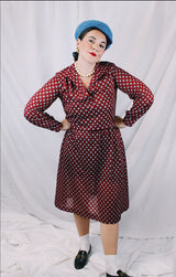Women's vintage 1970's long sleeve midi length lightweight polyester dress with v shaped neckline and collar. Cinched at waist with tie. Maroon with all over blue and tan print.