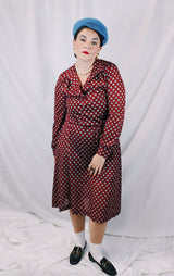 Women's vintage 1970's long sleeve midi length lightweight polyester dress with v shaped neckline and collar. Cinched at waist with tie. Maroon with all over blue and tan print.