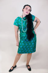 Women's vintage 1960's short sleeve midi length green and blue stain dress. Subtle floral print and scalloped waist. Zipper in the back.
