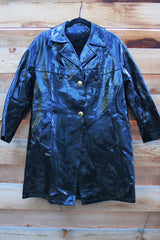 Women's vintage 1960's long sleeve black vinyl material jacket with gold buttons and hardware. Fully lined and has two side pockets.