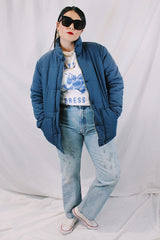 Men's or women's vintage 1980's long sleeve navy blue puffer jacket with zipper, popper buttons, and pockets. Cotton and polyester materials.