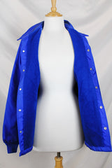 Women's or men's vintage 1980's Swingster, World of Wearables label long sleeve lightweight bright blue nylon windbreaker jacket with logo on left chest, popper buttons, and furry fleece liner.
