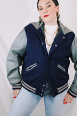 Men's or women's vintage 1980's Settlemein's, Portland, Oregon label long sleeve navy and grey varsity letterman jacket in wool, leather, and nylon. Snap buttons and hood.