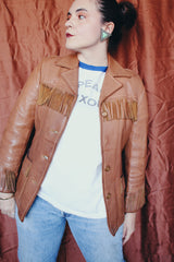 Women's vintage 1950's Custom Made by Milco-West, Portland, Oregon label long sleeve button up tan camel colored leather jacket with fringe trim. Western style with four pockets.