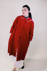 Women's vintage 1960's long length long sleeved red velvet robe duster with a peter pan collar and pink stain trim. Buttons up the front.