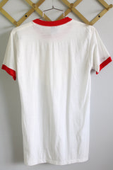 Women's or men's vintage 1970's Sneakers, Made in USA label short sleeve white t-shirt with red trim on neckline and cuffs with graphic on the front.