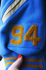 Men's or women's vintage 1994 Settlemien's, Portland, Oregon label long sleeve baby blue and cream varsity letterman jacket with yellow trim in leather and wool material.