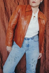 Women's or men's vintage 1970's Wilson label long sleeve burnt orange colored leather zip up jacket. Side pockets and dagger collar.