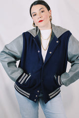 Men's or women's vintage 1980's Settlemein's, Portland, Oregon label long sleeve navy and grey varsity letterman jacket in wool, leather, and nylon. Snap buttons and hood.