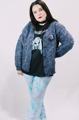 Women's vintage 1990's long sleeve acrylic knit button up cardigan in purple and blue colors with a flower pin.