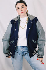 Men's or women's vintage 1980's Settlemein's, Portland, Oregon label long sleeve navy and grey varsity letterman jacket in wool, leather, and nylon. Snap buttons and hood.