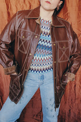 Women's or men 's vintage 1970's Montgomery Ward label long sleeve chocolate brown colored leather jacket with contrast stitching and popper buttons.