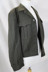 Women's or men's vintage cropped army jacket in a dark green grey wool material. Has a button closure and two front chest pockets.