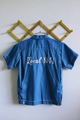 Women's or men's vintage 1960's Hilton, Made in USA label short sleeve blue button up bowling shirt with white trim and white embroidery.