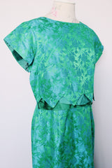 Women's vintage 1960's short sleeve midi length green and blue stain dress. Subtle floral print and scalloped waist. Zipper in the back.