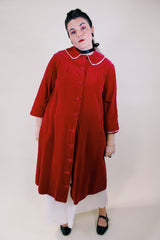 Women's vintage 1960's long length long sleeved red velvet robe duster with a peter pan collar and pink stain trim. Buttons up the front.