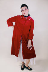 Women's vintage 1960's long length long sleeved red velvet robe duster with a peter pan collar and pink stain trim. Buttons up the front.