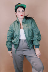 Men's vintage 1980's Flyer's CWU Military Flyer's Jacket, Made in USA label size medium long sleeve cropped length army green zip up bomber jacket with orange liner.