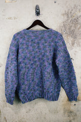 Women's vintage 1990's long sleeve acrylic knit button up cardigan in purple and blue colors with a flower pin.
